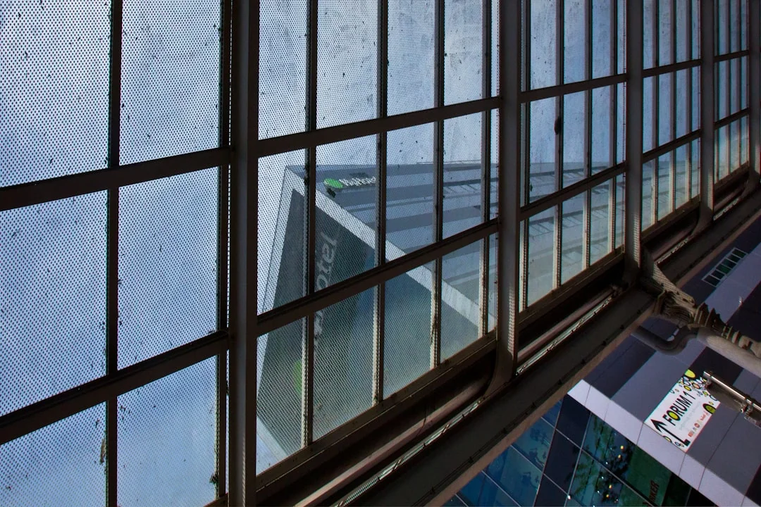 Two workers cleaning windows on a glass building facade using a lift platform, enhancing building aesthetics.