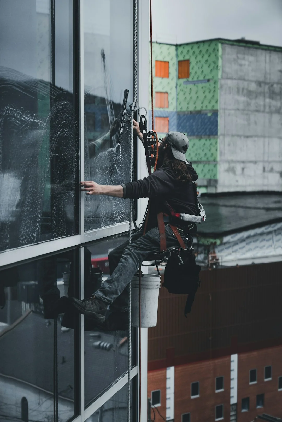 A man cleaning a glass door indoors using a spray bottle and cloth.